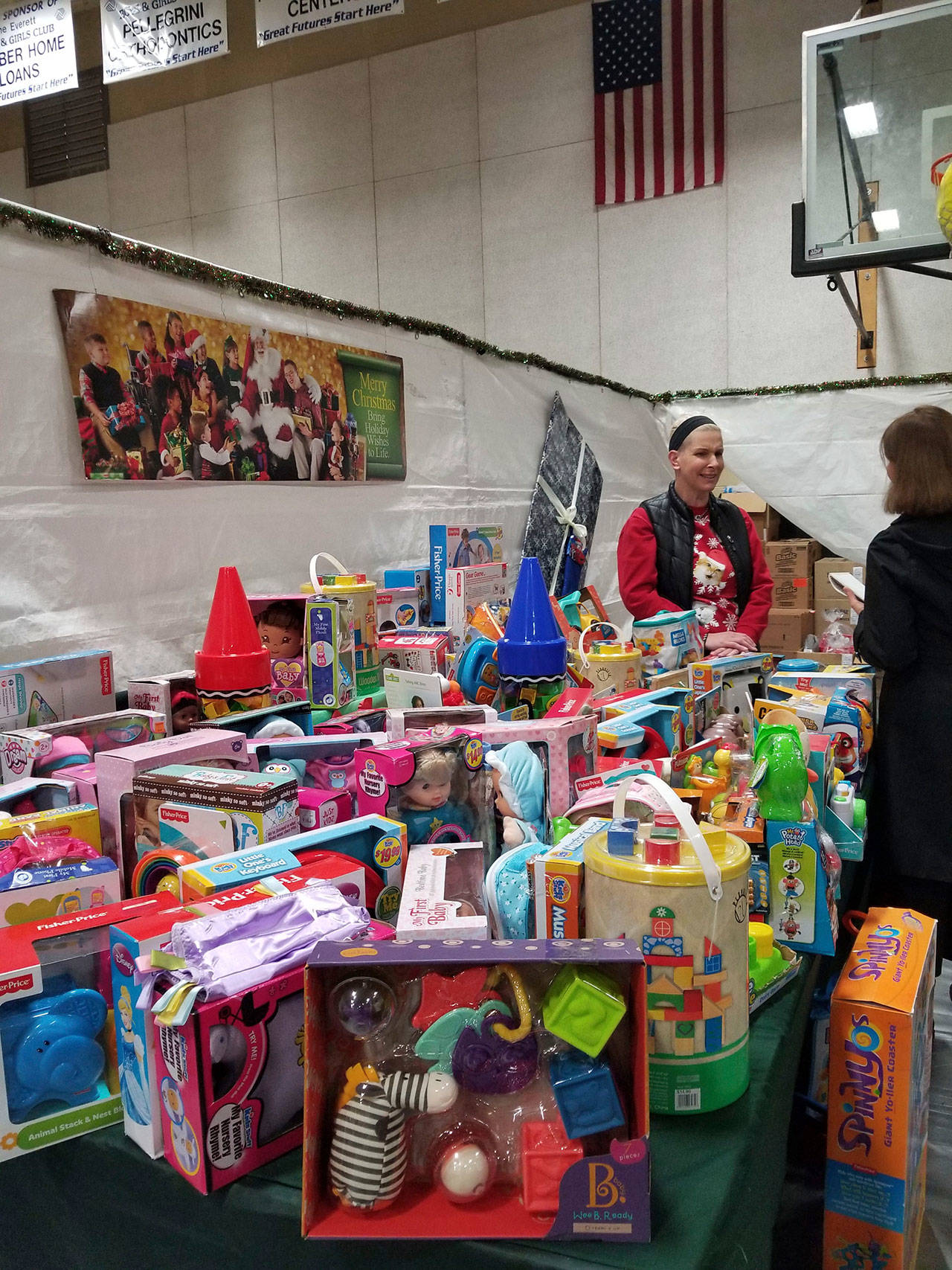 Tara Raimey, voluntaria de Christmas House, atendiendo una de las estaciones de juguetes gratuitos en Boys Girls Club de Everett. (Foto / La RazaNW)