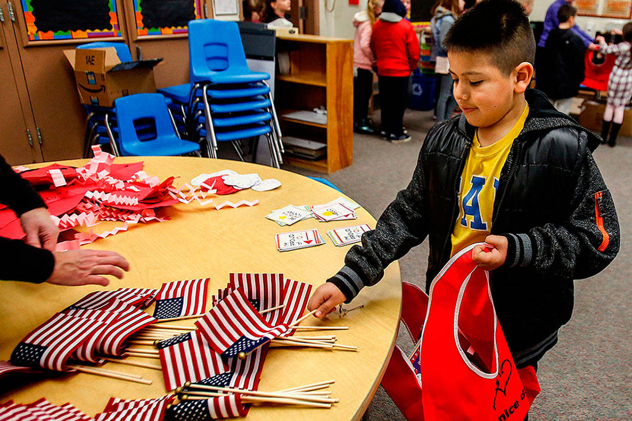 Eder Lara, de 9 años, de Emerson Elementary School, escoge una pequeña bandera estadounidense y la coloca en una bolsa de amigos como regalo para alguien en un asilo de ancianos local. (Dan Bates / The Herald)