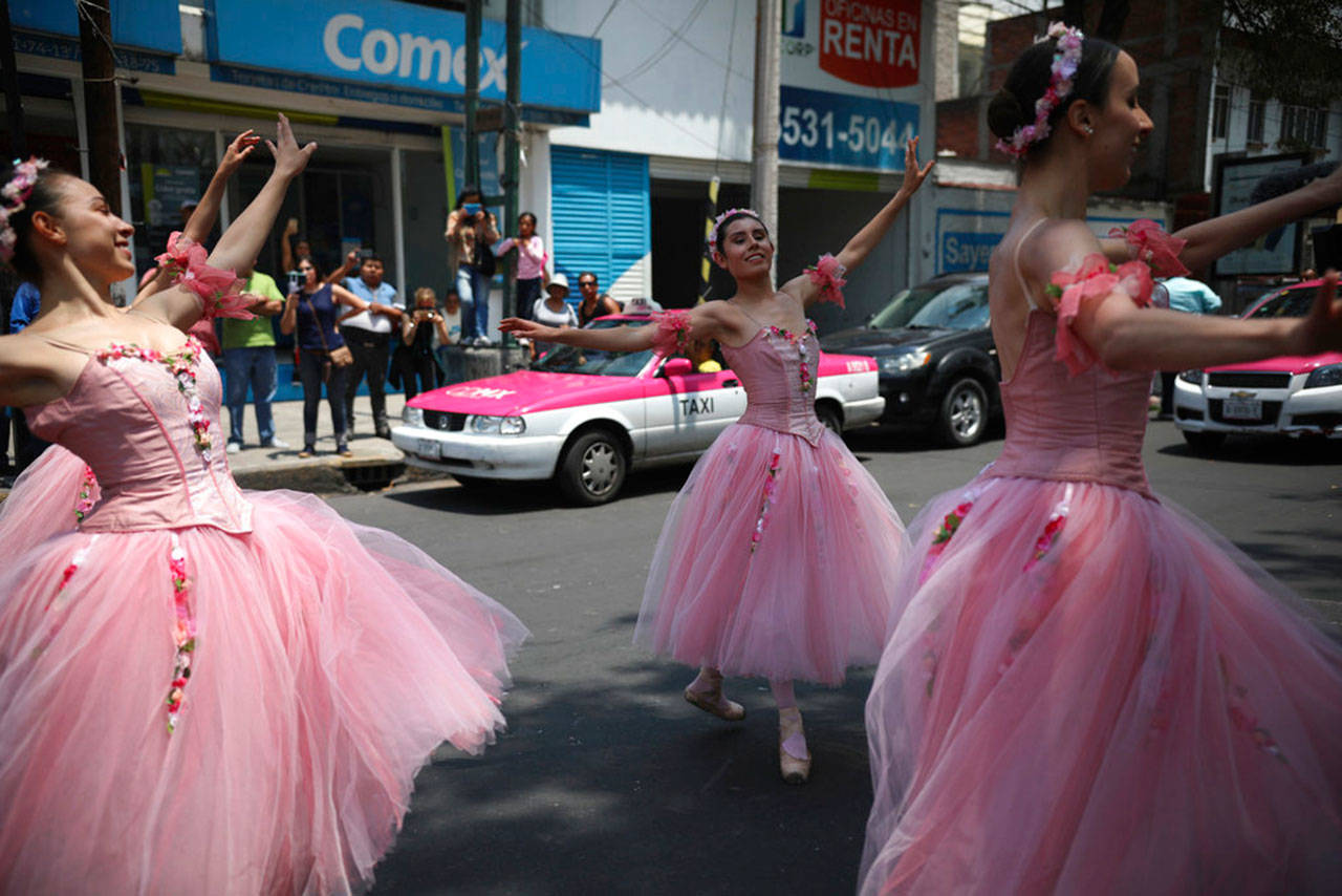 Las bailarinas bailan durante un semáforo en rojo, en la Ciudad de México, el sábado 28 de julio de 2018. En esta extensa megalópolis famosa por sus calles obstruidas, una compañía de teatro enviaba bailarines vestidos de tutú para deleitar a los automovilistas en cruces con fragmentos de clásicos del ballet como The Nutcracker y Swan Lake, todo en los 58 segundos que tarda la luz en pasar del rojo al verde. (AP Foto/Emilio Espejel)