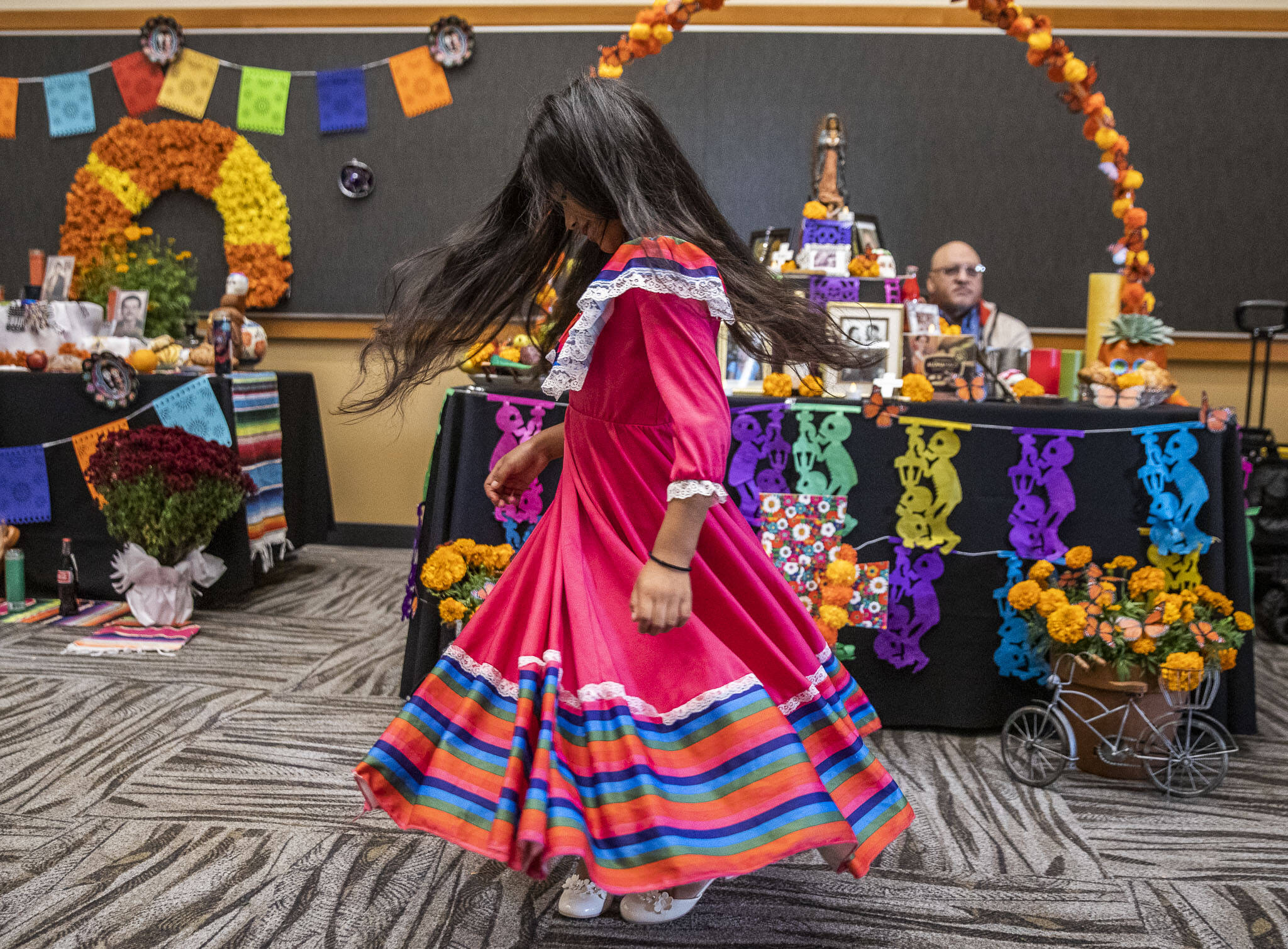 Belinda Reyes-Ordoñez, 7, spins in her dress while looking at the different ofrendas at the Washington-Guerrero Foundation’s Día de los Muertos event at the Lynnwood Convention Center on Saturday, in Lynnwood. (Olivia Vanni / The Herald)